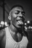 AI-generated night portrait of a young man in a white ribbed tank top, sweating and sticking out his tongue in a joyful street moment