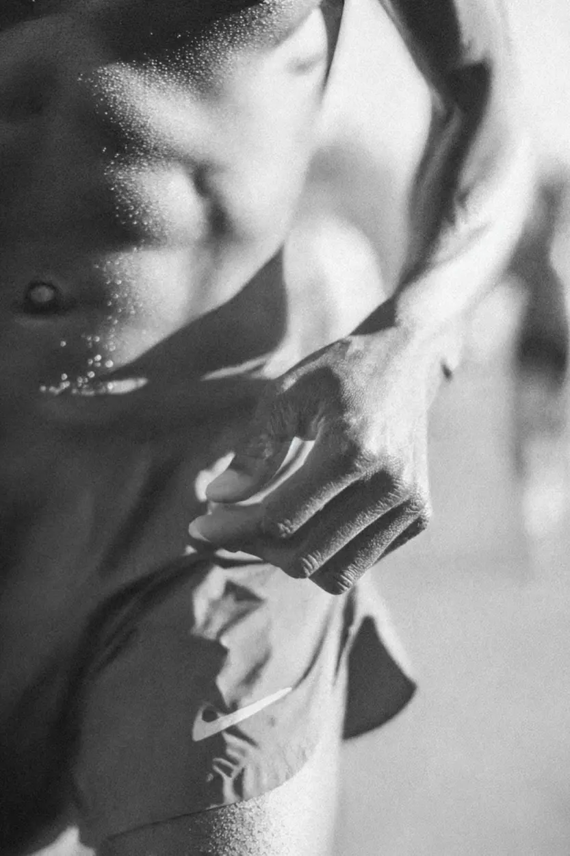 Close-up AI image of a runner mid-stride, focused on hand and torso with sweat and motion blur for realism